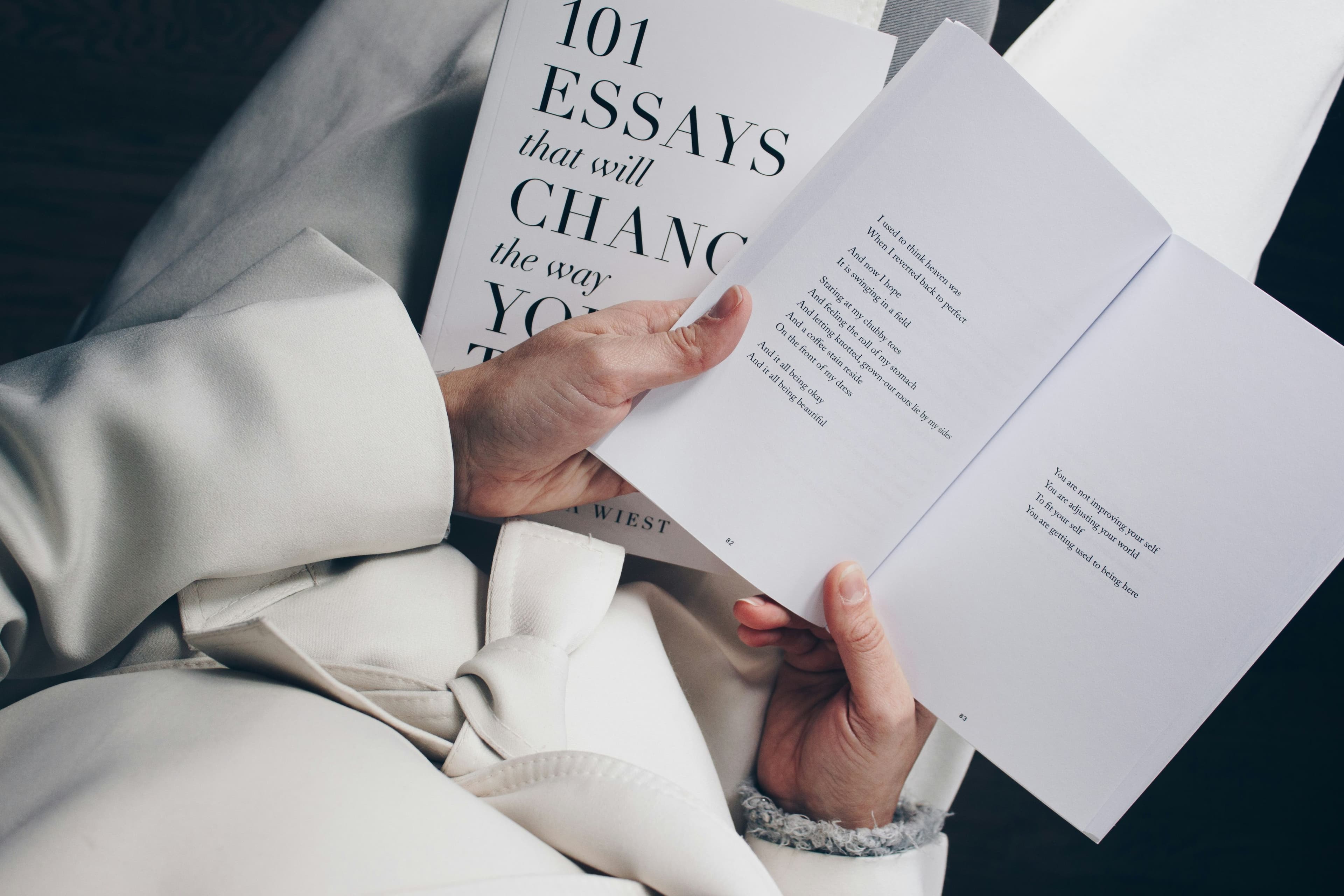 a woman holding a book with the title 100 essays that will change your life
